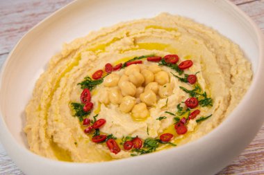 Homemade hummus with tahini plate with olive oil and paprika and pita isolated on brown background. High quality photo