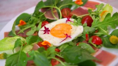 Mafya, roket, vişneli domates, pişirilmiş jambon ve balzamik soslu salata üzerine kızarmış yumurta. Yüksek kalite fotoğraf