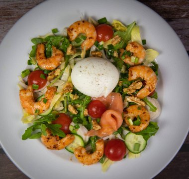 Roket salatası, hindiba, domates, salatalık, rafadan yumurta, kırmızı biberli kızarmış karides, füme somon ve fındık. Yüksek kalite fotoğraf