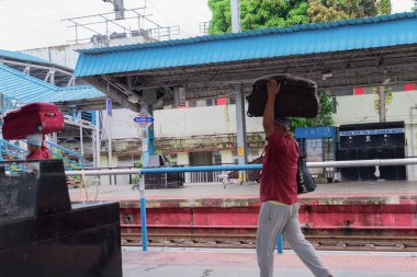Siliguri, Batı Bengal, Hindistan - 18 Ekim 2021: Hint demiryolu platformunda bir sürü çanta taşıyan bir işçinin odaksız görüntüsü. Coolie (koelie, kuli, cool, cool) - tren istasyonunda insanların çantalarını taşımak için para alan kişi.