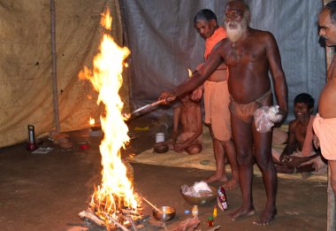 Sadhu baba (keşiş) Varanasi 'de kutsal ateşin altında duruyor. Ateşe odaklan..