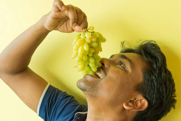 Homem Indiano Saudável Comendo Algumas Uvas Isoladas Sobre Verde Imagem De Stock
