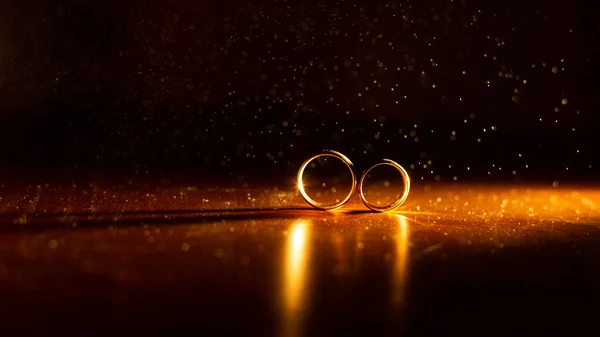 Dwa Pierścienie Stole Oświetlone Złotym Światłem Pięknym Bokeh Pyłu — Zdjęcie stockowe
