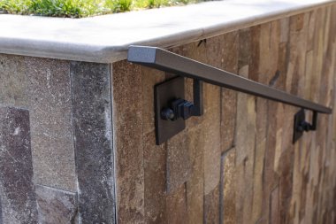 Evin yakınındaki taş duvarda modern metal parmaklıklar var..