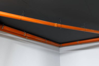 Modern bir evin sakinleri için yeraltı otoparkındaki turuncu kanalizasyon boruları. Bodrumda teknik borular ve elektrik var..