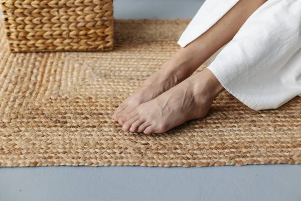 Nazik bacaklar, beyaz odada paspas üzerinde meditasyon yapan genç, kırılgan ve hamile bir kadının yakınına..