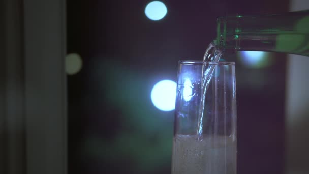 Champán se vierte en una copa de una botella, fondo de la ventana — Vídeos de Stock