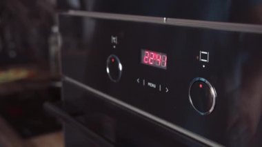 Adam fırın panelindeki modları değiştiriyor. Erkek eli fırını açmak için düğmeyi çevirir.