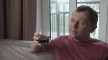 Adam evde oturup elinde bardakla elinde içki tutarken hayal kurar.