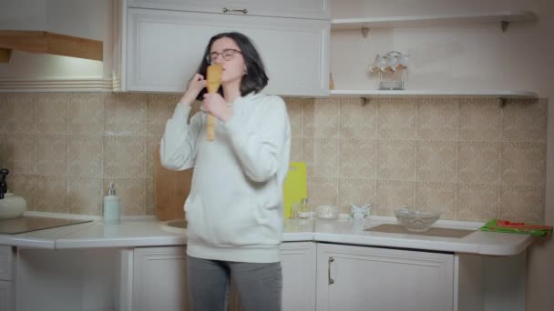 Chica morena en gafas divirtiéndose en el fondo de la cocina — Vídeo de stock