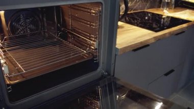Erkekler tepsiyi tavuk bacağı ve patates dilimleriyle birlikte fırına koyar. Kapatın, kamera takibi.