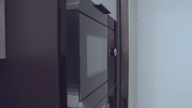 Adam buzdolabından bir tabak yiyecek çıkarıyor ve ısınmak için mikrodalgaya koyuyor.