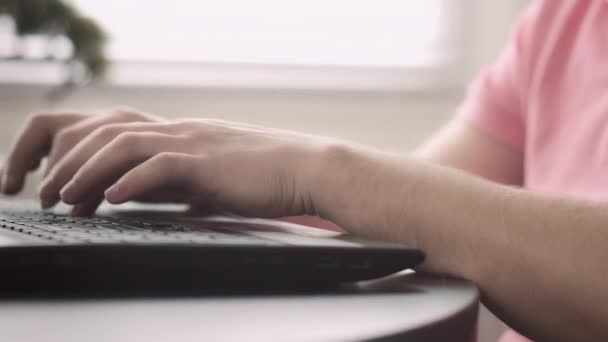 Manos de un hombre con una camiseta rosa que trabaja en una computadora portátil, rastreando cámaras — Vídeo de stock