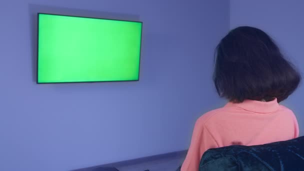 Mädchen vor einem Fernseher, der an der Wand hängt, Nachrichten guckt, chromakey, Rückansicht — Stockvideo