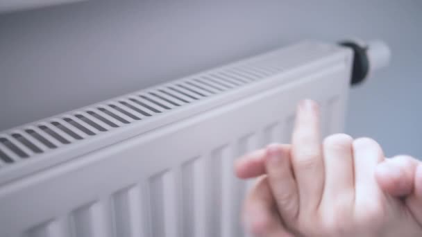 A man warms his hands with his fingers on the radiator — Stock Video