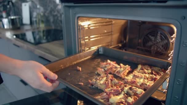 Mannen tar en bit hemlagad pizza från ugnen och lägger en spatel på tallriken. — Stockvideo