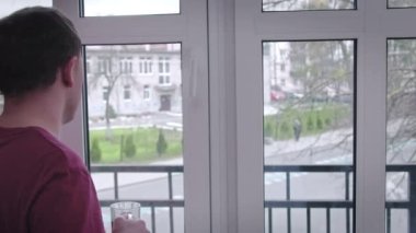 Adam kahve içiyor ve pencereden sokakta neler olduğunu izliyor.