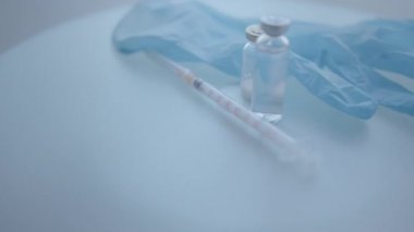 Tıbbi eldivenler, şırınga, ilaç şişesi yüzeyde dönüyor, seçici odaklanma