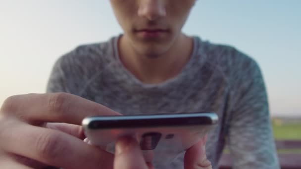 Il ragazzo legge messaggi di testo sulla sua app cellulare e sorride, primo piano — Video Stock