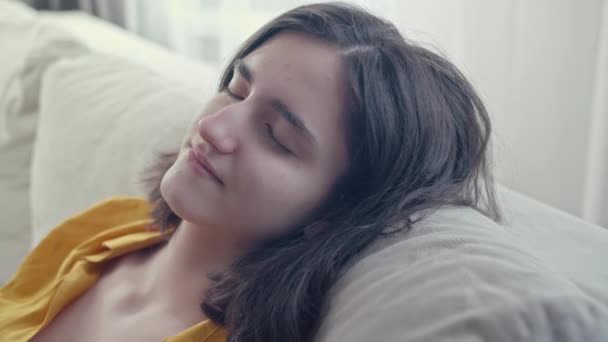 Chica morena relajada y tranquila sentada en un cómodo sofá, disfrutando del resto — Vídeos de Stock
