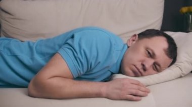 Mavi tişörtlü genç bir adam zor bir günün ardından kanepeye yığıldı.