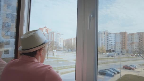 Чоловік Капелюсі Рожева Футболка Стоїть Балконі Дивлячись Вулицю Через Відкрите — стокове відео