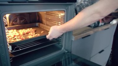 Bir adam fırından bir parça ev yapımı pizza alır ve tabağına ahşap bir spatula koyar, kamera takibi.