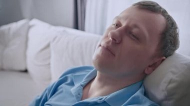 Kanepeye oturup gözlerini kapayan, rahatlama konsepti, mekanı kopyalayan genç bir adamın portresi.