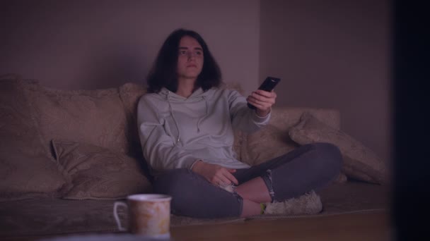 Menina sentada em casa à noite e assistindo TV enquanto sentado no sofá — Vídeo de Stock