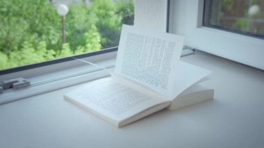 Pencerenin kenarında açık bir pencere var Açık bir kitap, güneşli bir gün