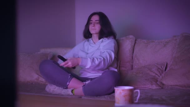 Mädchen verbringt die Nacht zu Hause, fernsehen, während sie auf der Couch sitzt, Abendbeleuchtung — Stockvideo