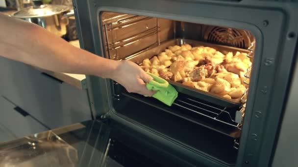 L'homme sort un dîner fait maison du four sur un plateau et met de la nourriture dans son assiette, suivi de la caméra — Video