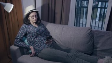 Bir kız öğrenci akşamları koltukta otururken cep telefonundan mesajları okur.