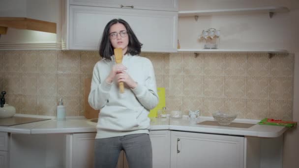 Chica en gafas es divertirse bailando y cantando en el fondo de la cocina en casa, emociones positivas — Vídeos de Stock