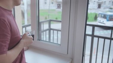 Bir adam kahve içiyor ve pencereden sokakta neler olduğunu izliyor.