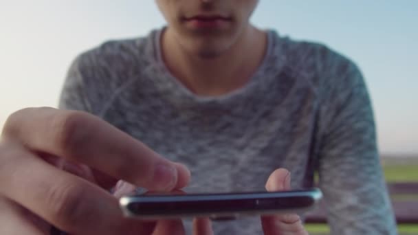 Ręce faceta z telefonem komórkowym, przegląda wiadomości tekstowe w aplikacji mobilnej jego telefonu i uśmiecha się, zbliżenie — Wideo stockowe