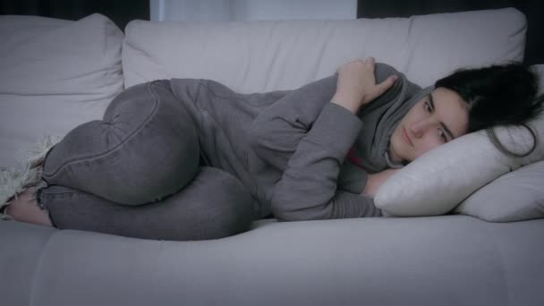 Smutna dziewczyna leży na kanapie przytulając się do seby, przygnębiony nastrój, pojęcie rozstania i straty — Wideo stockowe