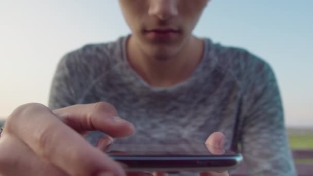 Mani di un ragazzo con un telefono cellulare, legge messaggi di testo nell'applicazione mobile del suo telefono, primo piano — Video Stock
