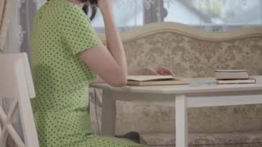 Masada oturan yeşil elbiseli kız kitap okuyor.