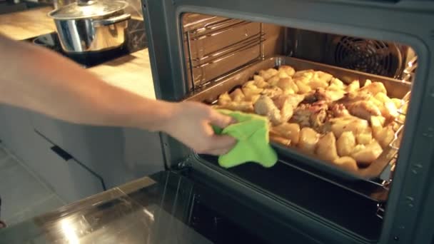 L'uomo mette il cibo cucinato in casa su un vassoio in forno e mette il cibo sul suo piatto, Ringraziamento, monitoraggio della telecamera — Video Stock