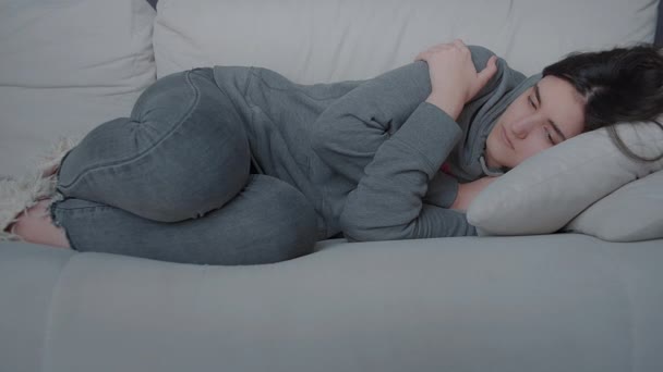 Одинокая девушка лежит неподвижно на диване, камера слежения — стоковое видео