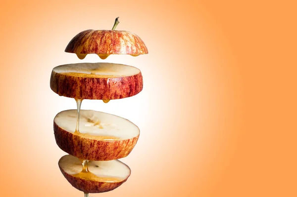 新鲜切碎的红苹果和蜂蜜滴在飞舞的食物中 带有悬浮的倒影 感冒药和强身健体 超级食品早餐橙背景 — 图库照片