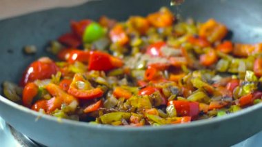 Arka planda 4K rengarenk buharlı sebzelerin tavada kızarması ve karıştırılması görüntüsü. Yemek pişirme, sağlıklı yemek, vejetaryen mutfağı. Lezzetli tat, ev yapımı yemek.