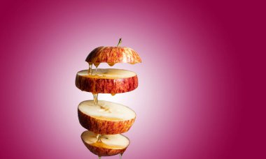 Taze dilimlenmiş kırmızı elma ve bal havada asılı duran yiyeceklere damlıyor. Alternatif şeker ikamesi, soğuk ilaç ve vücut güçlendirme, süper gıda kahvaltısı kırmızı zemin.