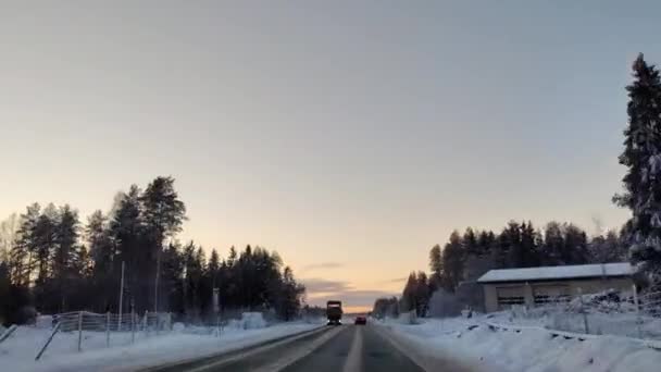 在4K时差的情况下在白雪覆盖的路上开车 清澈的天空 阳光普照在松树顶上 冬季景观下汽车驾驶的超差凸轮视图 — 图库视频影像
