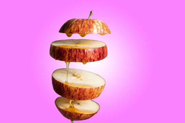 新鲜切碎的红苹果和蜂蜜滴在飞舞的食物中 带有悬浮的倒影 感冒药 强身健体 超级食品早餐粉红背景 — 图库照片