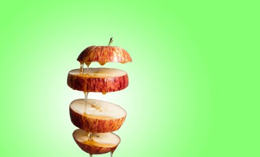 Taze dilimlenmiş kırmızı elma ve bal havada uçuşan yiyeceklere damlıyor. Alternatif şeker ikamesi, soğuk ilaç ve vücut güçlendirme, süper gıda kahvaltısı yeşil arka plan.