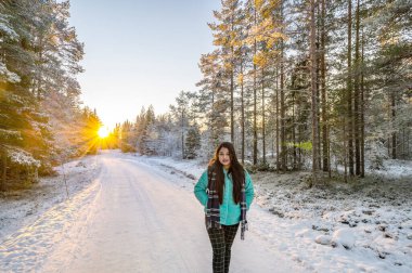 Karlarla kaplı ağaçların sakin manzarası kar yığınları ve güzel günbatımı. Siyah ceketli güzel bir kadın Sihirli Kış Ormanı 'nda yürüyor. Bulutlu gökyüzü ile doğal manzara. 