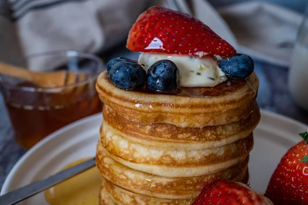 一堆堆堆放蜂蜜 蓝莓和奶油的煎饼放在盘子里 还有美味的早餐甜点 — 图库照片