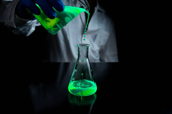 과학자가 개발을 어두운 실험실에 모양의 플라스크에서 용액을 가지고 실험을 있습니다 로열티 프리 스톡 사진